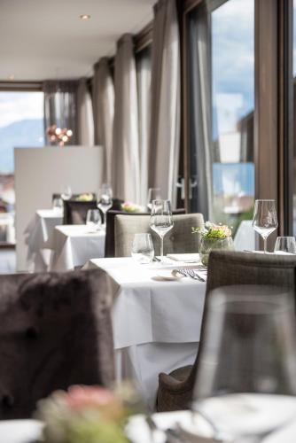 a restaurant with white tables and chairs with wine glasses at Hotel - Appartements Schmied Hans in Schenna
