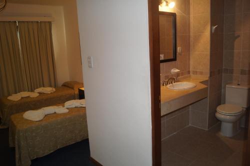 a bathroom with two beds and a sink and a toilet at Grand Hotel by MH in Termas de Río Hondo