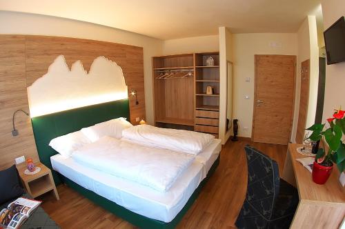 a bedroom with a large white bed in a room at Botton d'Oro delle Dolomiti in Vattaro