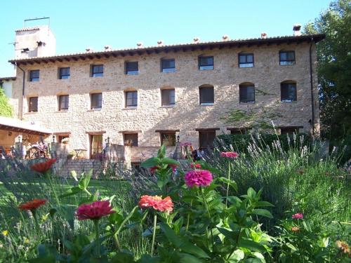 a large stone building with flowers in front of it at Font del Pas in Beceite