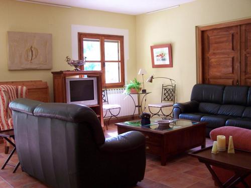 a living room with black leather furniture and a tv at Font del Pas in Beceite