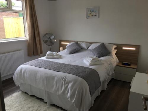 Exmouth holiday home في اكسماوث: غرفة نوم بسرير كبير مع شراشف بيضاء ونافذة