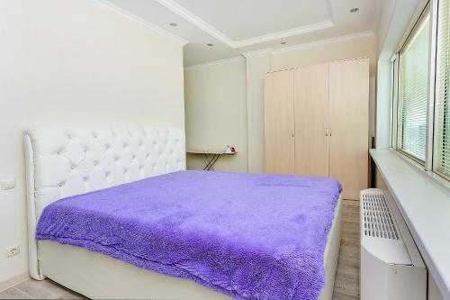een witte slaapkamer met een paarse deken op een bed bij Studio on Dostyq Street 5 floor 25 in Astana