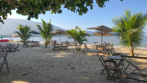 a sandy beach with tables and chairs and umbrellas at HOTELARE Hotel Brunello in Paraty
