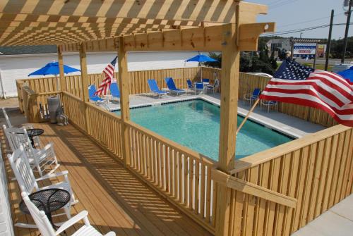 an outdoor pool with an american flag and chairs at Outer Banks Inn in Kill Devil Hills