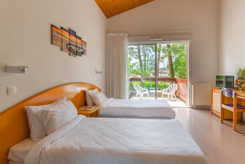a hotel room with two beds and a balcony at Azureva Ronce les Bains in Ronce-les-Bains