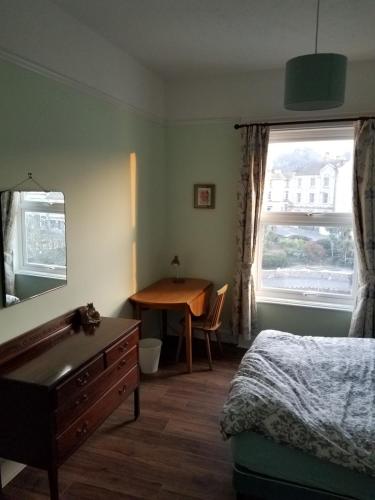 a bedroom with a bed and a desk and a window at Dawlish Sea View Apartment in Dawlish