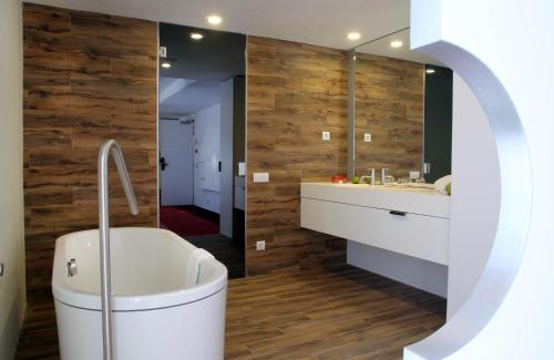 a bathroom with a tub and a sink and a mirror at Room Mate Pau, Barcelona in Barcelona