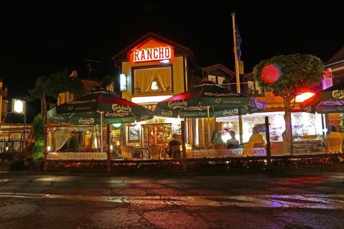 a restaurant with umbrellas on a street at night at Rancho Willa & Restaurant in Rewal
