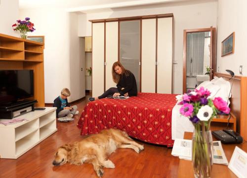 Eine Frau auf einem Bett mit einem Hund auf dem Boden in der Unterkunft Hotel Helvetia in Genua