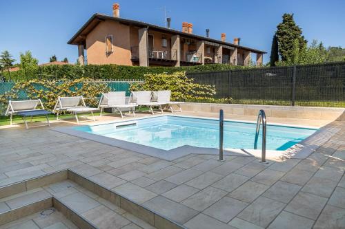 a pool with chairs and a house in the background at Casa Pepe in Colà di Lazise
