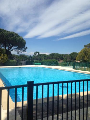 une grande piscine bleue à côté d'une clôture dans l'établissement Agréable studio proche StTropez Piscine et Tennis, à Gassin