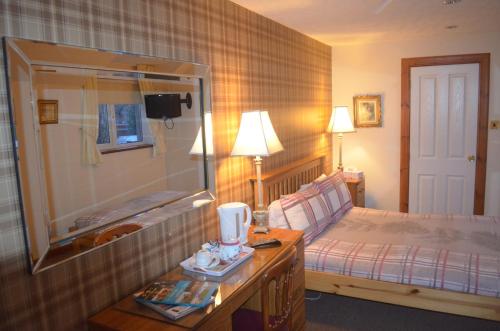 a bedroom with a bed and a table with a mirror at Roseneath Guest House in Inverness