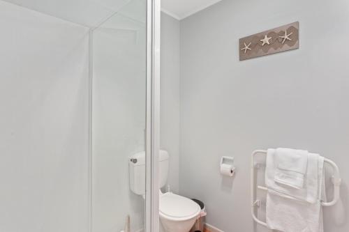 a bathroom with a toilet and a glass shower at Ohope Heights in Ohope Beach
