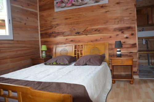 ein Schlafzimmer mit einem Bett und einer Holzwand in der Unterkunft Fleur des iles in Bras-Panon