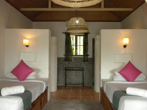 two beds in a room with a fireplace at Raingsey Bungalow in Kep