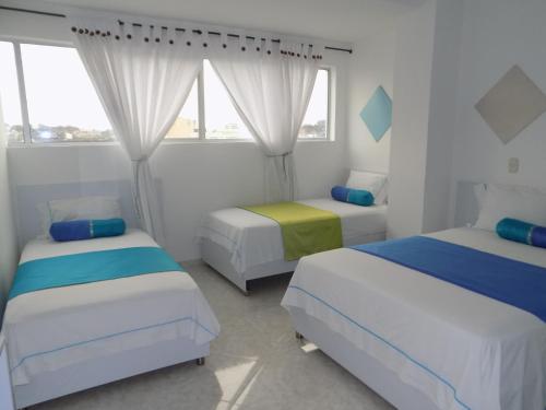a bedroom with two beds and two windows at Hotel Luna Azul in Florencia