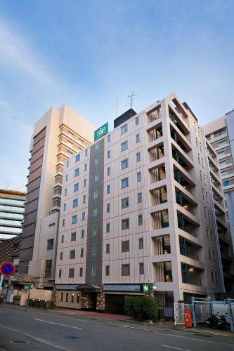 a large white building with a street sign on top at Washington R&B Hotel Hakata Ekimae 1 in Fukuoka