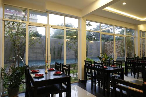 a dining room with tables and chairs and large windows at Holy Angkor Hotel in Siem Reap