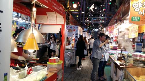a group of people walking around a food market at MK Guesthouse in Busan