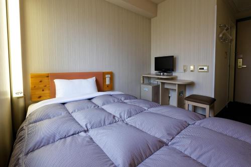 een slaapkamer met een groot bed met paarse kussens bij R&B Hotel Kumamoto Shimotori in Kumamoto