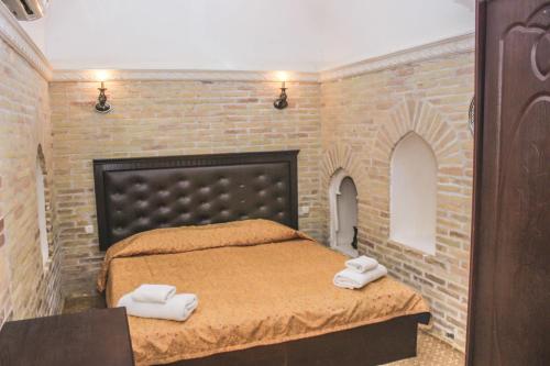 a bedroom with a brick wall and a bed with towels at Orient Star Khiva Hotel- Madrasah Muhammad Aminkhan 1855 in Khiva