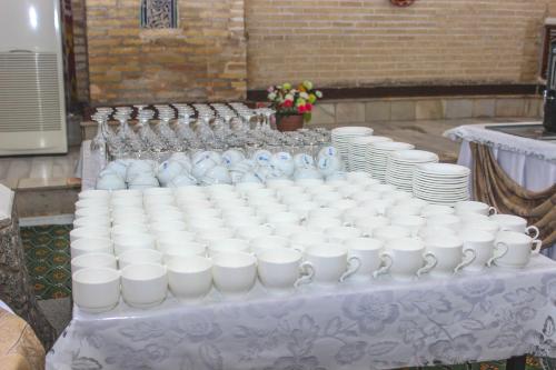 a table with a bunch of white jars and plates at Orient Star Khiva Hotel- Madrasah Muhammad Aminkhan 1855 in Khiva