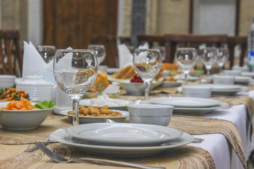 a table with plates of food and wine glasses at Orient Star Khiva Hotel- Madrasah Muhammad Aminkhan 1855 in Khiva