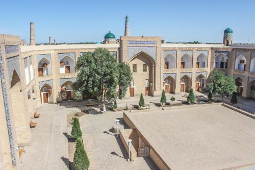 a large building with a courtyard with trees in front of it at Orient Star Khiva Hotel- Madrasah Muhammad Aminkhan 1855 in Khiva