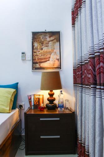 a bedroom with a bed and a table with a lamp at Sanctuary Cove Guest House in Polonnaruwa