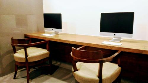 two computer monitors sitting on a desk with chairs at Ginger Mumbai, Andheri in Mumbai