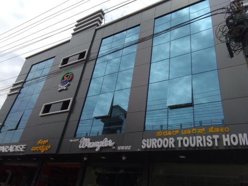 a building with a sign on the side of it at Suroor Tourist Home in Virajpet