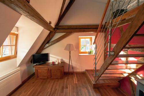 a attic room with a staircase and a television at La Maison d'Emilie in Pfaffenheim