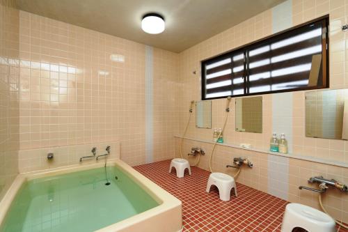 a bathroom with a tub and a toilet and a sink at Minshuku Kojima in Nozawa Onsen