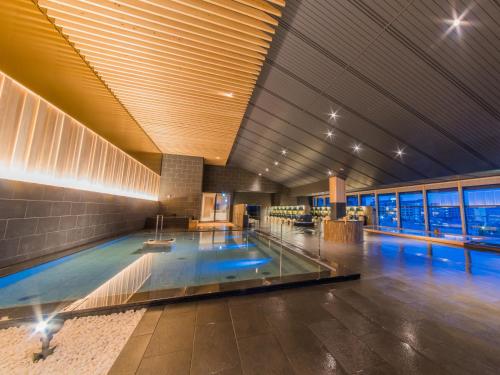 a swimming pool in a large building with a swimming pool at Grandia Housen in Awara