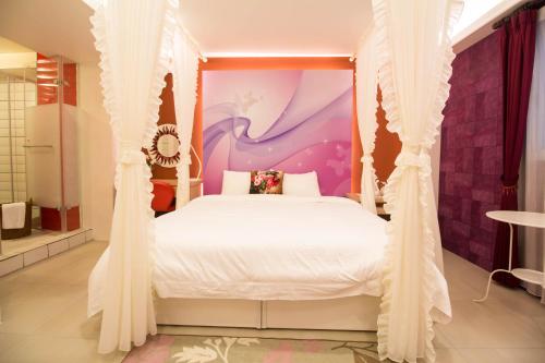 a bedroom with a white bed with a purple wall at Bei Yue B&B in Luodong