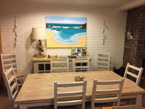 a dining room table with chairs and a painting on the wall at The Retreat on Matthew in Batehaven