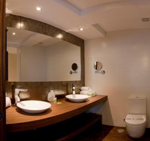 a bathroom with two sinks and a large mirror at Hotel Os Olivos in Guísamo