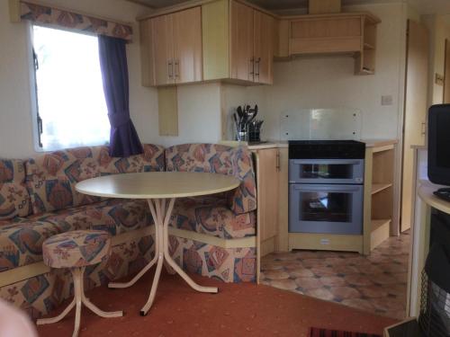 Una cocina con una mesa y un sofá y una mesa. en Cosy Caravan at Blackmoor Farm, en Ludchurch