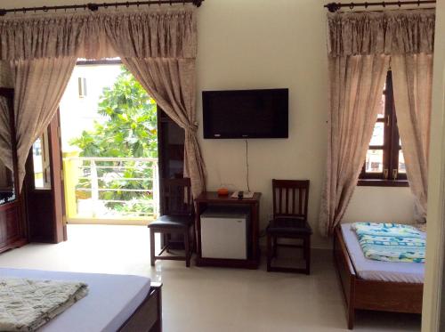 a bedroom with a bed and a tv on the wall at Quoc An Hotel in Long Hai