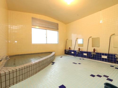 ein großes Bad mit einer Badewanne und einem Pool in der Unterkunft Lodge Tsubaki in Otari