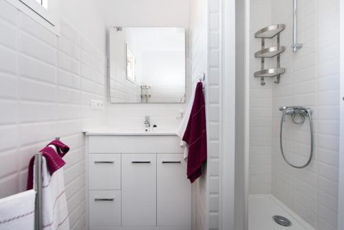 ein weißes Badezimmer mit Waschbecken und Spiegel in der Unterkunft Two-Bedroom Apartment Diosa Tanit in Alicante