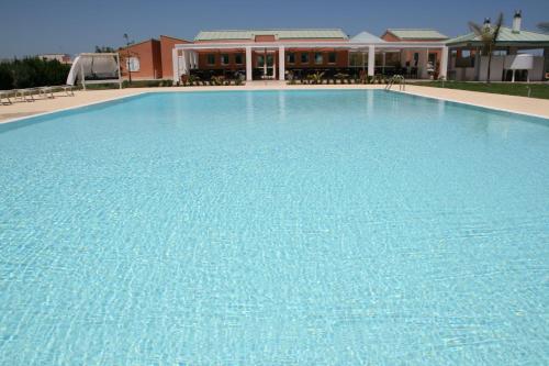 a large blue swimming pool in front of a building at Hotel Villa Fanusa in Siracusa