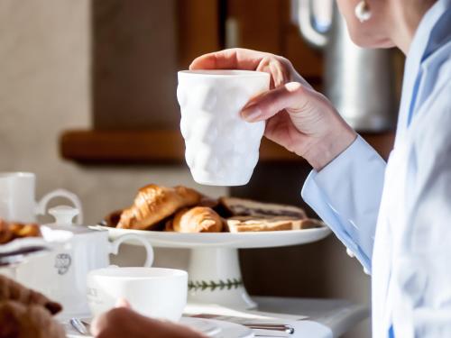a woman holding a cup of yogurt with a plate of donuts at Alice Relais Nelle Vigne in Vittorio Veneto
