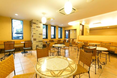 ein Restaurant mit Tischen, Stühlen und Fenstern in der Unterkunft R&B Hotel Nagoya Sakae Higashi in Nagoya
