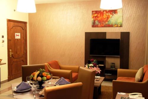 a living room with a table and chairs and a television at Spark Residence Hotel in Sharjah