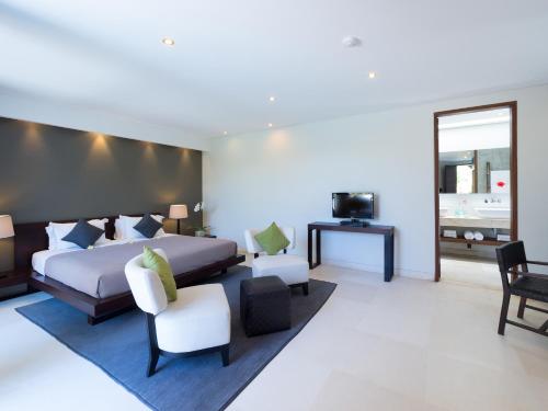 a bedroom with a bed and chairs and a television at The Layar - Designer Villas and Spa, CHSE Certified in Seminyak