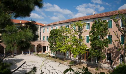 a large building with trees in front of it at Ostello Bassano Del Grappa in Bassano del Grappa