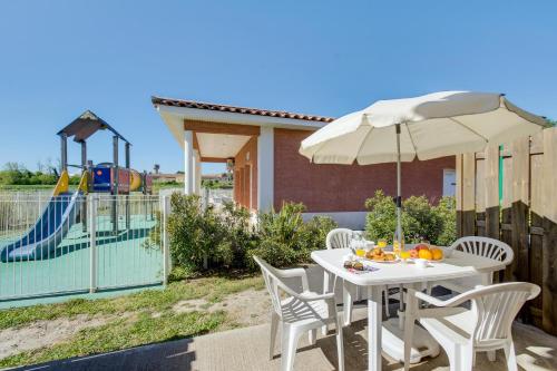 une table et des chaises avec un parasol et une aire de jeux dans l'établissement Vacancéole - Le Domaine d'Enserune, à Colombiers