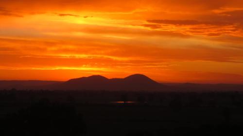an orange sunset with mountains in the background at Stone Creek Cottage in Barwite